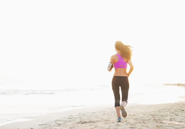 Healthy young woman running on beach - Фото, изображение