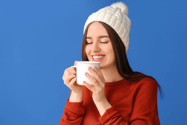 Beautiful young woman with cup of hot cocoa on color background - Фото, изображение