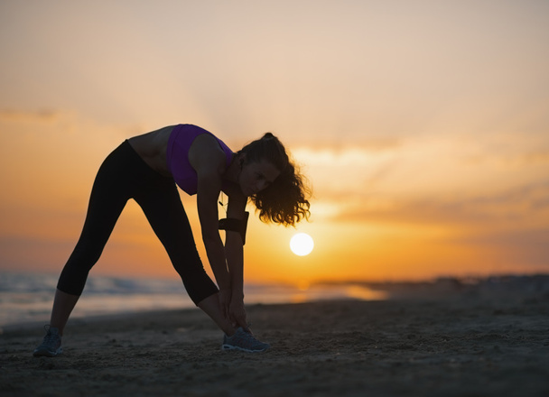 Silhouette of fitness young woman making exercise on beach - Fotoğraf, Görsel