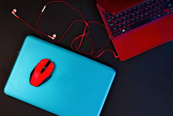 Top view of two colored laptops, turquoise and red, headphones and red computer mouse on the blue one - Fotoğraf, Görsel