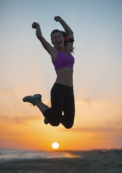 Silhouette einer jungen Frau, die in der Abenddämmerung am Strand springt - Foto, Bild