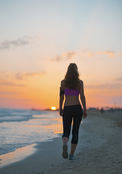 Fitness young woman walking on beach at dusk - Foto, imagen