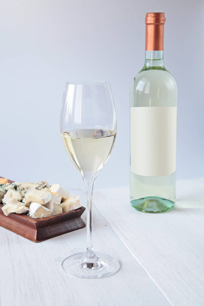 木製のテーブルの上にワインとチーズのボトル - 写真・画像