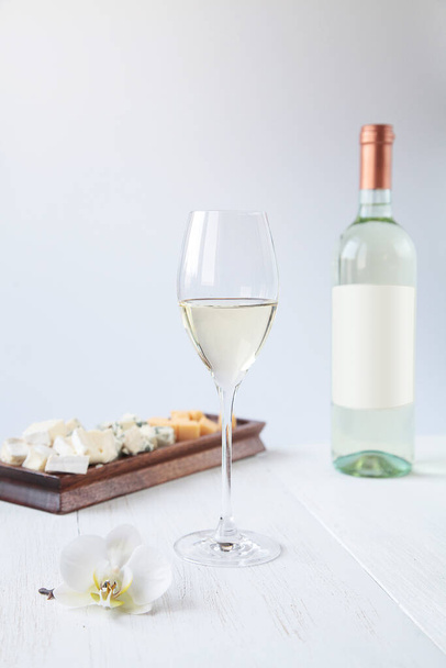 Glas Wein, Flasche und Orchideen auf einem weißen Holztisch - Foto, Bild