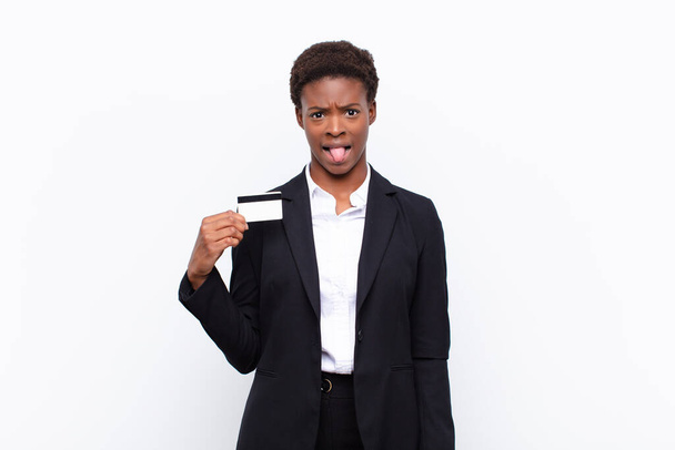 young pretty black womanfeeling disgusted and irritated, sticking tongue out, disliking something nasty and yucky holding a credit card - 写真・画像