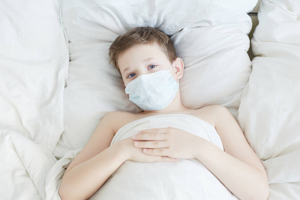 Kleine jongen in Masker. Epidemisch concept. Coronavirus. Kind in bed. in quarantaine geplaatst medisch gemaskeerd kind. - Foto, afbeelding