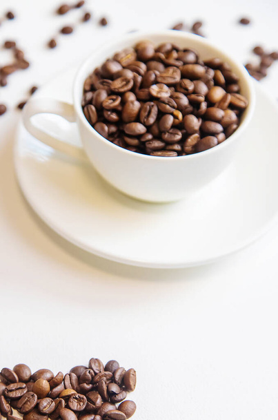 taza blanca y granos de café sobre un fondo blanco. Enfoque selectivo
. - Foto, Imagen