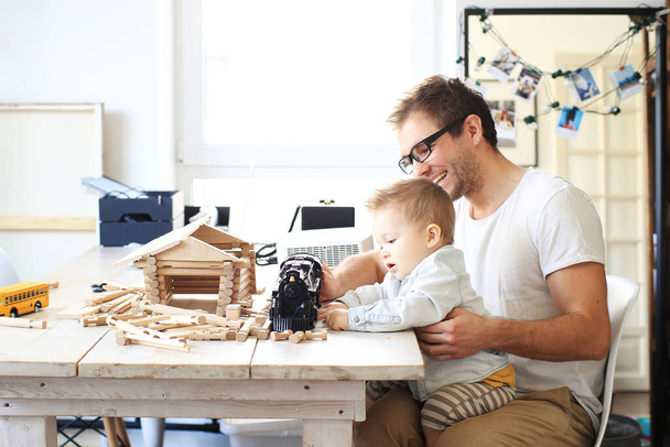 Father and young son sit and play on the table - 写真・画像