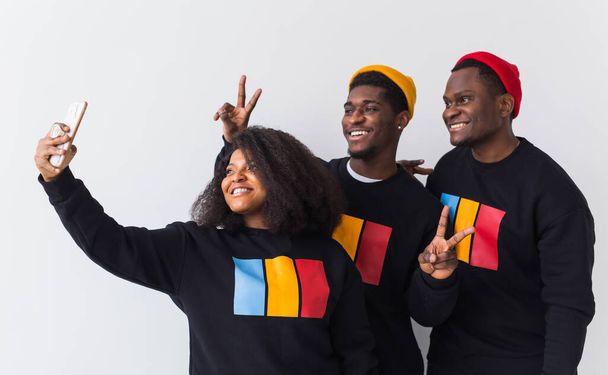 Vriendschap en leuk concept - vriendengroep afro-Amerikaanse mannen en vrouwen nemen selfie in studio op witte achtergrond. - Foto, afbeelding