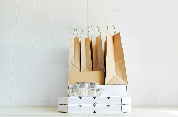 Delivery during quarantine.Takeaway paper bags and carton boxes on table on white background. - Foto, Imagen