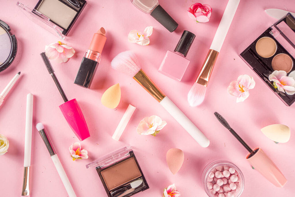 Makeup products with cosmetic bag and spring flowers. Professional Makeup set flatlay. Set of decorative cosmetics on tender pink background. Copy space above - Photo, Image