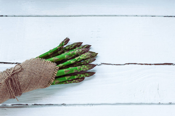 Green fresh asparagus on white wooden table. Healthy food concept. Top view, flat lay, copy space. - Fotó, kép