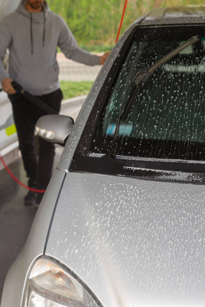 Чоловік миє машину на автомийці самообслуговування
. - Фото, зображення