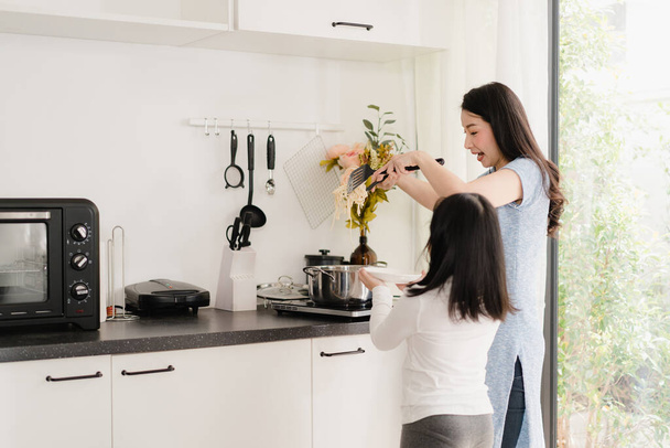 junge asiatische japanische Mutter und Tochter kochen zu Hause. Lifestyle-Frauen freuen sich, gemeinsam Pasta und Spaghetti zum Frühstücksgericht in der modernen Küche im Haus am Morgen zuzubereiten. - Foto, Bild