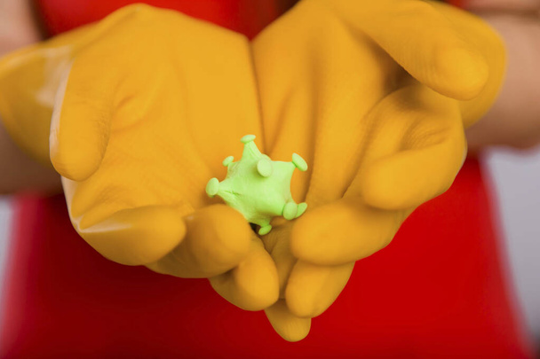 Closeup cleaning woman's hands with coronavirus model on yellow gloves. Concept art of cleaning the premises and the prevention of viral diseases. - Photo, Image