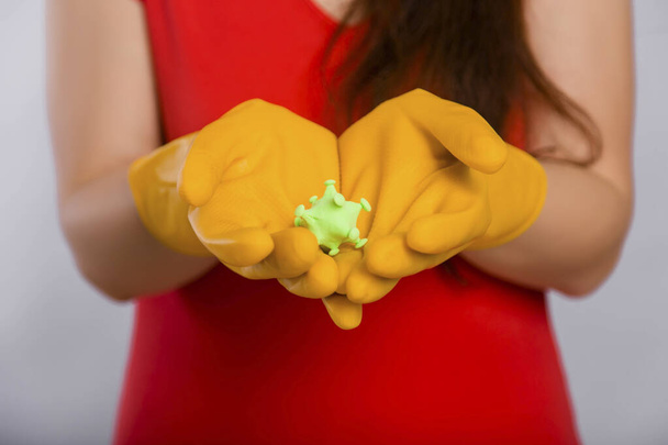 Primer plano limpiando las manos de la mujer con el modelo coronavirus en guantes amarillos. Concepto de arte de la limpieza de los locales y la prevención de enfermedades virales
. - Foto, imagen