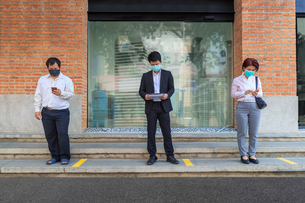 Азиатские люди среднего возраста носят маску и сохраняют социальное дистанцирование, чтобы избежать распространения COVID-19 - Фото, изображение