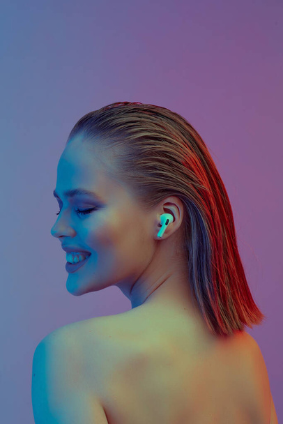 A beautiful young girl in wireless headphones listens to song with a good mood. bright colorful music poster. - Foto, Bild
