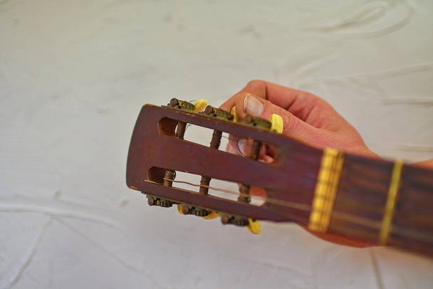 Ujjak forgatja a hangoló csapok és fogaskerekek a fejen egy akusztikus gitár. Behangolom a gitárt. Részleteket egy régi akusztikus gitár fejéről. Fénymásolási hely. - Fotó, kép