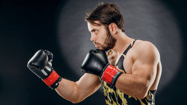 A man in Boxing gloves. A man Boxing on a black background. The concept of a healthy lifestyle. - Φωτογραφία, εικόνα