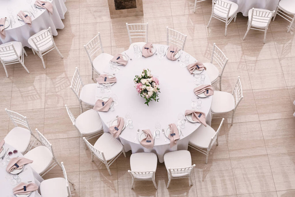 Το πολυτελές στρογγυλό τραπέζι για το γεύμα του γάμου είναι διακοσμημένο με λουλούδια και κομψά πιάτα. - Φωτογραφία, εικόνα