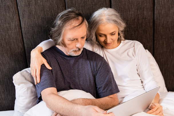 mature couple looking at laptop in bed at home  - Foto, Imagem