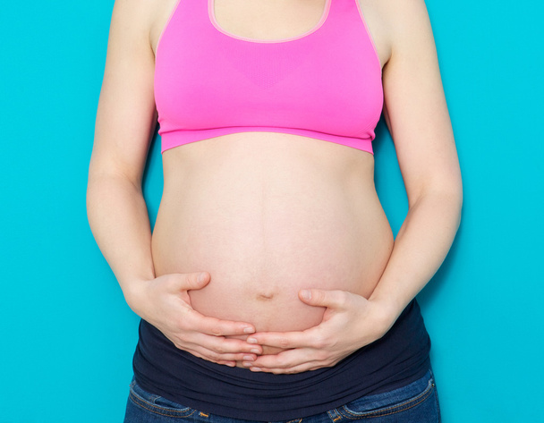 Close up mother holding pregnant stomach - Fotografie, Obrázek