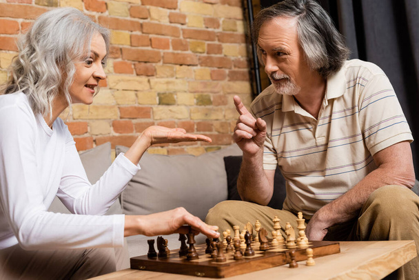 volwassen man en vrouw schaken in woonkamer  - Foto, afbeelding