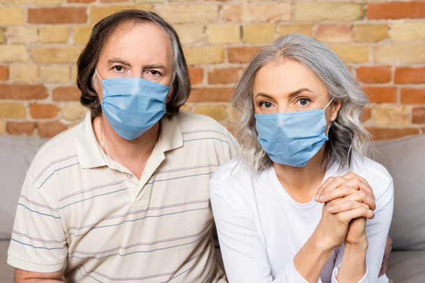 Ältere Paare in medizinischen Masken schauen in die Kamera   - Foto, Bild