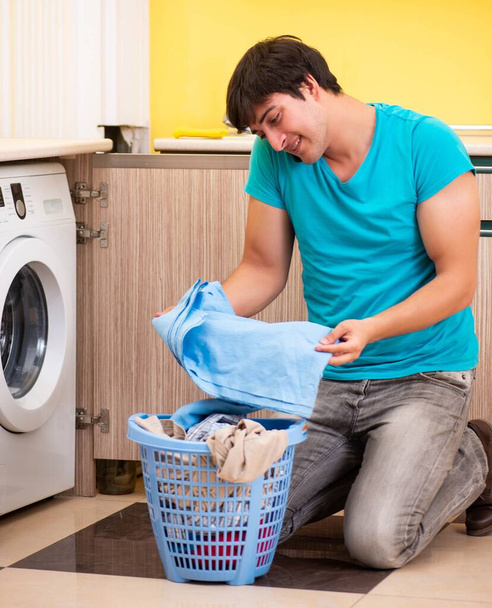 A fiatal férj otthon mossa a ruháit. - Fotó, kép