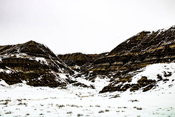 A hó a puszták hegyeibe és völgyeibe kapaszkodik. Drumheller Alberta, Kanada. - Fotó, kép