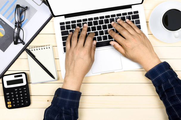 podnikatel pracující s moderním pracovištěm s laptopem na dřevěném stole, Muž ruka na notebooku klávesnice pro práci z domova, Overhead pohled na podnikatele pracující v kanceláři - Fotografie, Obrázek