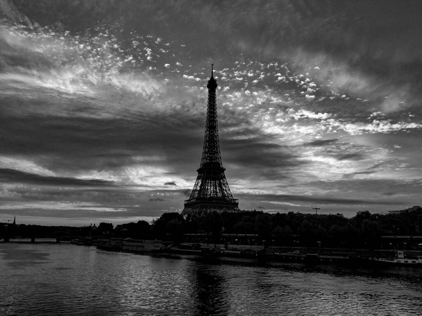 Schwarz-Weiß-Fotografie vom frühen Morgen auf der Seine mit Blick auf den Eiffelturm und einen schönen wolkenverhangenen Himmel in Paris, Frankreich - Foto, Bild