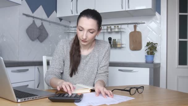Genç bir kadın yüksek vergiler, faturalar ya da ipotek oranı yüzünden stresli ve üzgün hissediyor. Ev ödemeleri hesaplanıyor. Muhasebeci, banka borcu faturasını hesaplamak için evden çalışıyor. - Video, Çekim