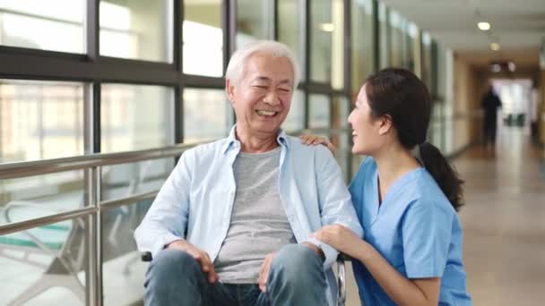 дружелюбный азиатский работник разговаривает с инвалидной коляской связанный пожилой человек резидент в коридоре вспомогательного жилья
 - Кадры, видео