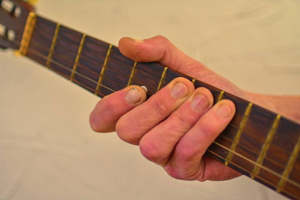 Рука людини, яка грає на старій акустичній гітарі. Стара гітарна голова з настроювальними кілочками
. - Фото, зображення