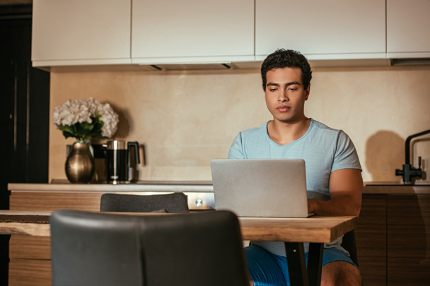 beau mâle mixte freelance travail avec ordinateur portable sur la cuisine pendant la quarantaine
 - Photo, image