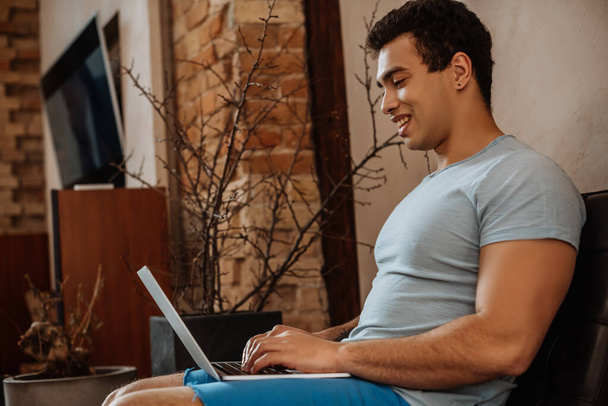 happy mixed race man chilling with laptop at home on quarantine - Valokuva, kuva