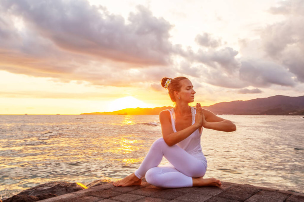Woman practices yoga at seashore - 写真・画像
