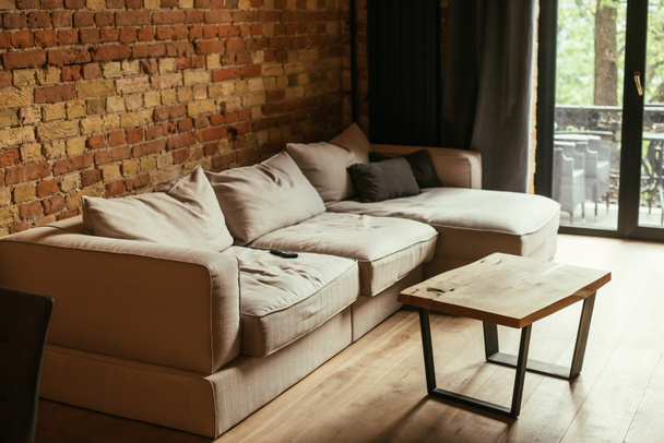 modern interieur van woonkamer met beige bank, tafel en afstandsbediening - Foto, afbeelding