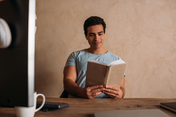 šťastný smíšený závod freelancer čtení knihy v domácí kanceláři během karantény - Fotografie, Obrázek