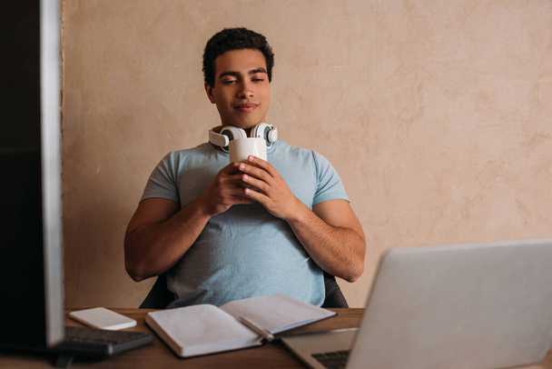 Mixed Race Freelancer mit einer Tasse Kaffee, der während der Quarantäne im Home Office arbeitet - Foto, Bild