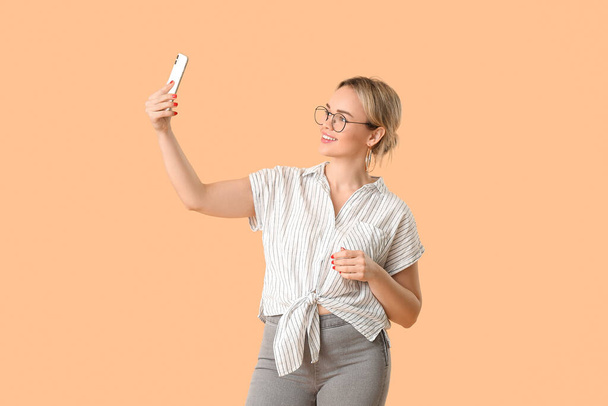 Portret van mooie jonge vrouw met mobiele telefoon op kleur achtergrond - Foto, afbeelding