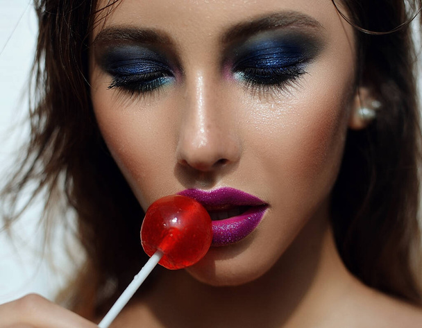 beautiful sexy wet girl portrait with colorful makeup in the summer is hot with a candy in his mouth - Photo, Image