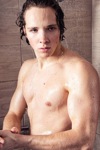 Young handsome guy in the shower. - Фото, изображение