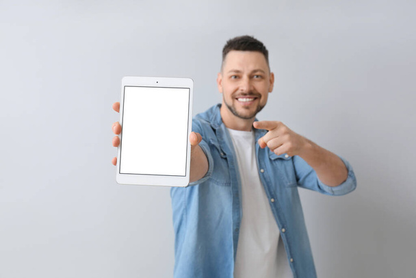 Handsome man with tablet computer on grey background - Photo, Image