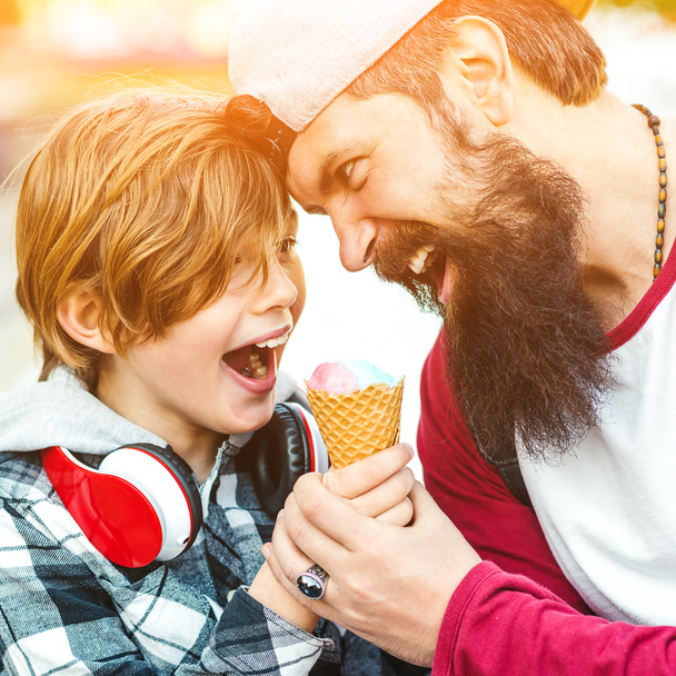 Un mignon gamin qui mange une glace dans un cône. Père et fils s'amusent ensemble. Vacances d'été. Glace de fruits savoureux pour la famille. Père et fils passent un bon moment en promenade
. - Photo, image