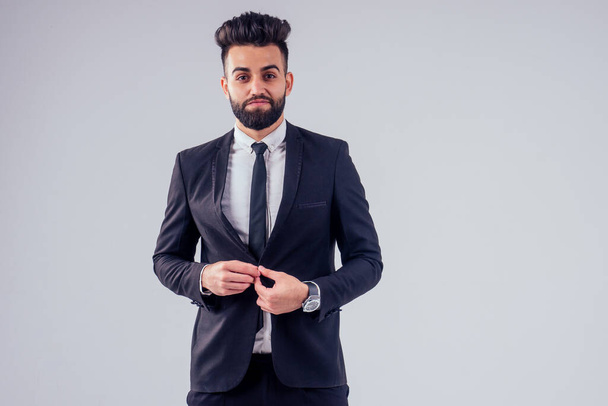 young turkish handsome black hair man in stylish business suit knotting the tie in studio isolate white background - Foto, afbeelding