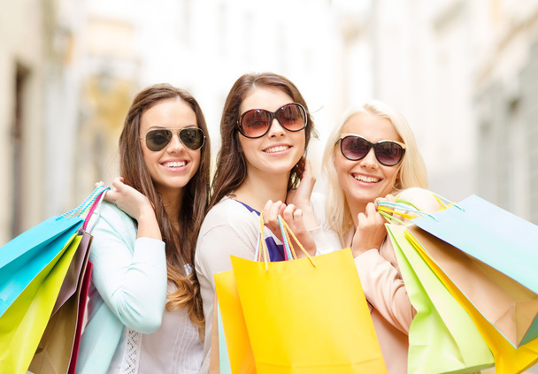Three smiling girls with shopping bags in city - Foto, imagen