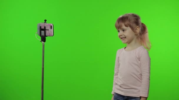 Menina criança faz selfie vlog, blogging, vídeo call on mobile phone using monopod
 - Filmagem, Vídeo